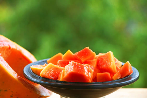 Papaya slice cut and served in a plate with the green natural background Papaya slice cut and served in a plate with the green natural background papaya stock pictures, royalty-free photos & images
