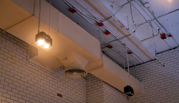 istock Ceiling lamp with opened light and air duct hanging on ceiling. Air conditioner pipe system. Air ventilation system. Fire sprinkler pipe. Cool system in building. Building interior architecture. 1162493848