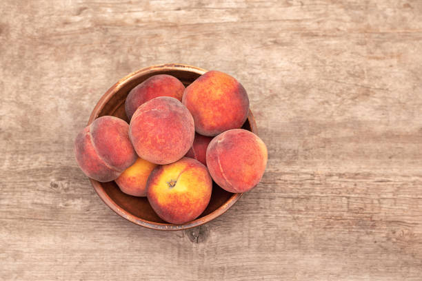 istock Ripe peaches in a bowl on wooden background. 1162497509