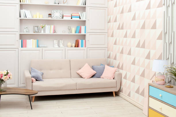 istock Pastel-coloured interior with beige sofa and built-in bookcase 1162500517