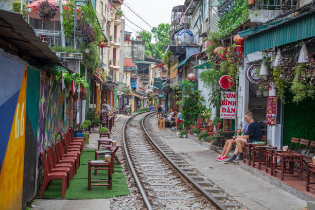 o bairro antigo, as trilhas de trem da rua de hanoi. atravessando as ruas estreitas. vida dos moradores na rua com um trem - vietnam asia hanoi street - fotografias e filmes do acervo