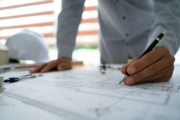 istock Architect hands working on blueprint plans  with  a pencil,  a ruler, calculator, smartphone, laptop and engineering tools 1162502133