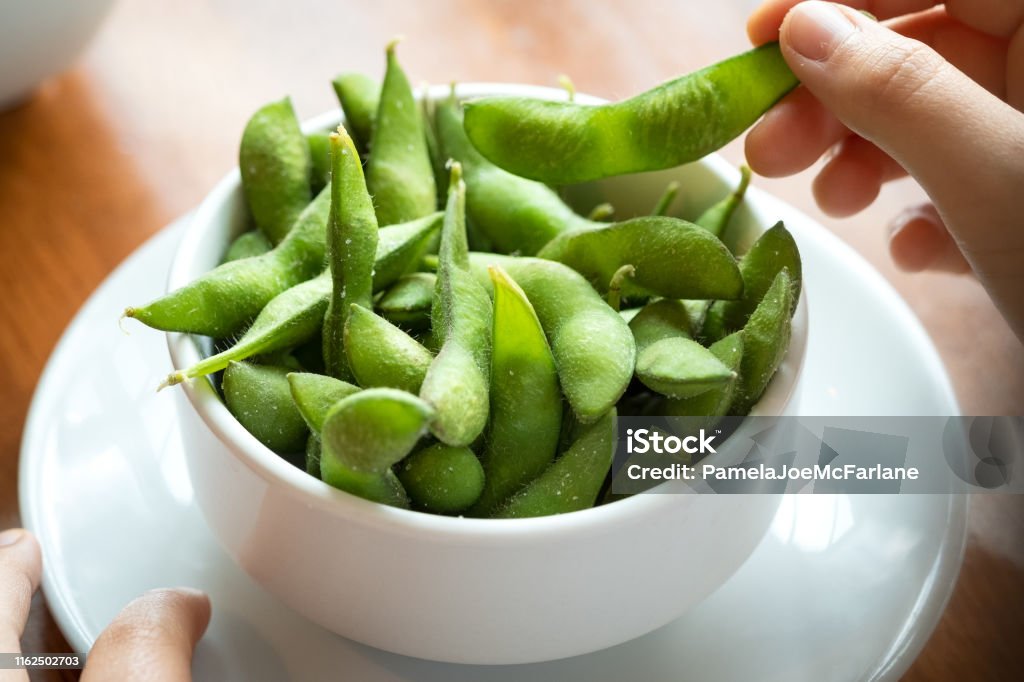 POV, Salted Edamame Beans, Eating Japanese Food by Hand Personal perspective of a diner eating a Japanese meal. Edamame Stock Photo