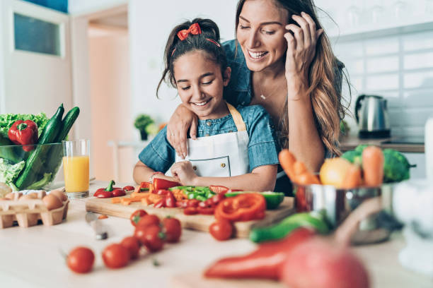 madre enseñando a su hija a cocinar - vegetable cutter fotografías e imágenes de stock