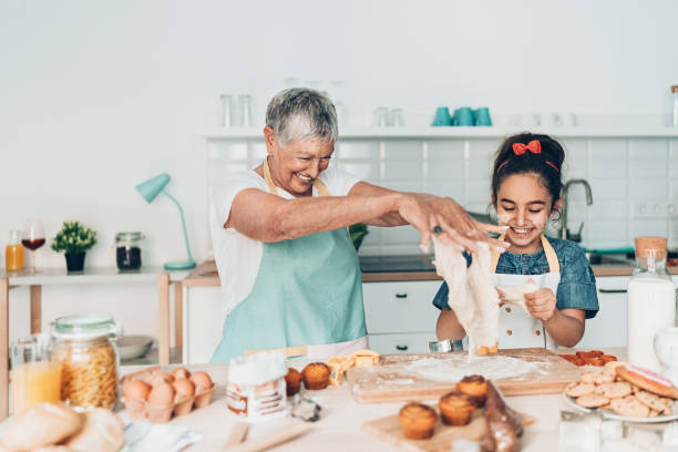 abuela y nieta jugando con masa de galletas - grandmother generation gap senior adult granddaughter fotografías e imágenes de stock