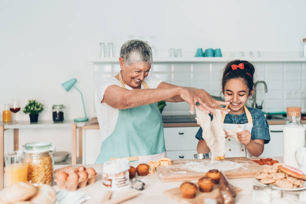 grandmother and granddaughter playing with cookie dough - grandmother cooking baking family imagens e fotografias de stock