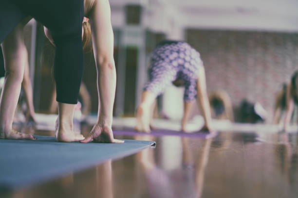 Group of asian young woman stretching and practices practicing during their yoga class in a gym. fitness, sport, training, yoga and people concept
