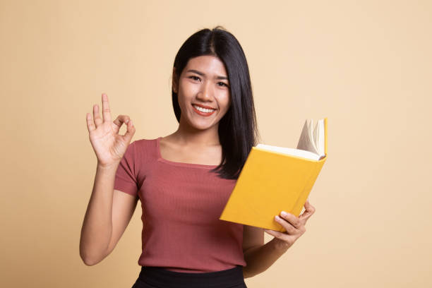 istock Young Asian woman show OK with a book. 1162518572