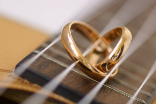 Wedding ring in a heart shape laying on ukulele guitar strings.