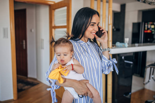 istock Mom babysitting and talking on mobile at home 1162519915
