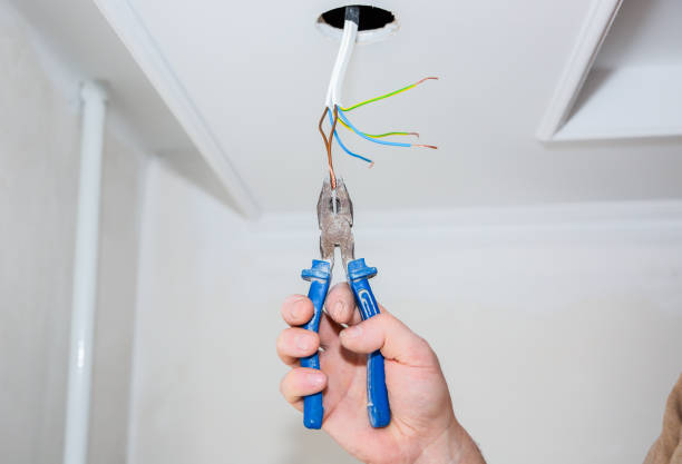 istock Man is holding pliers in his hands. Electrical insulator for light bulb. Adhesive tape for maintenance repair works in the flat. Restoration indoors. 1162520162