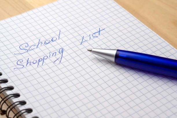 istock Blue pen on a notebook with sheets in a cage. Sign - school shopping list 1162524873