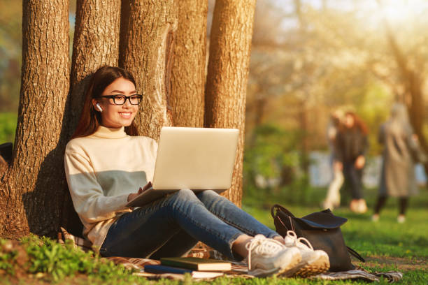 나무 근처 노트북앉아 행복한 소녀 - laptop computer grass nature 뉴스 사진 이미지