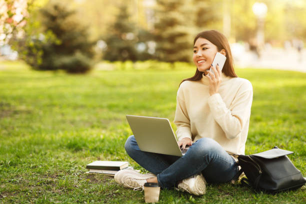 istock University life. Student girl talking on phone and using laptop 1162525998