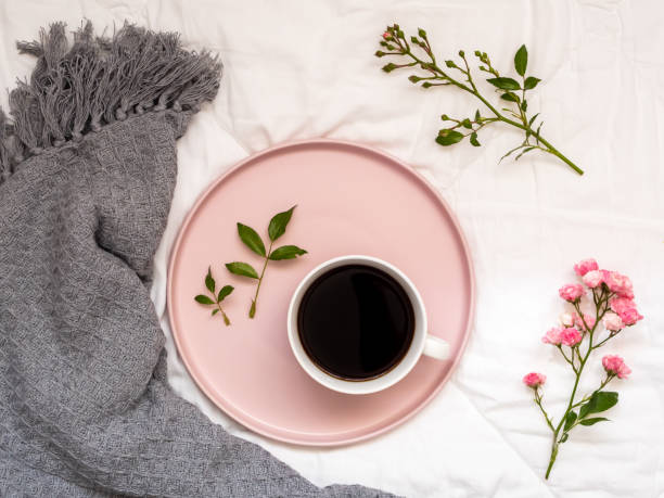 istock Coffee cup and flowers on a white coverlet 1162529919