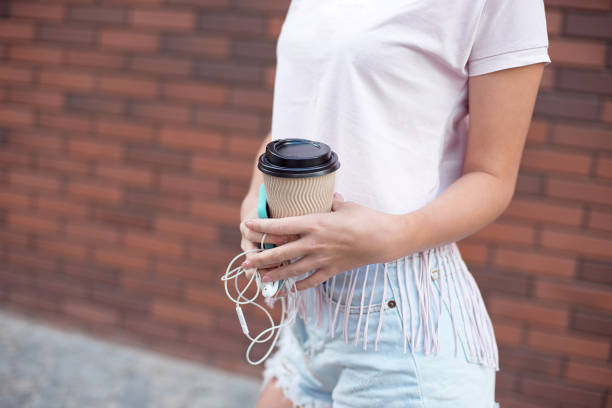 istock Young woman with mobile phone and coffee on a red brick background 1162529971