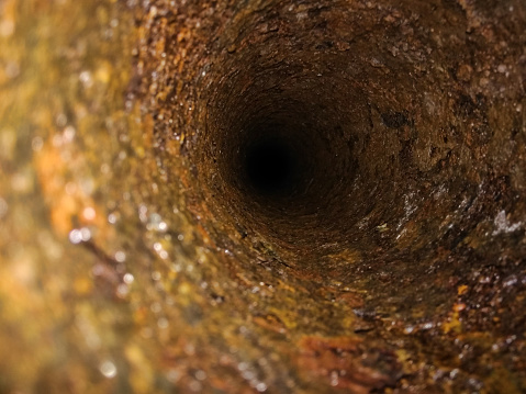 Inside rusty pipe. Sewage collector