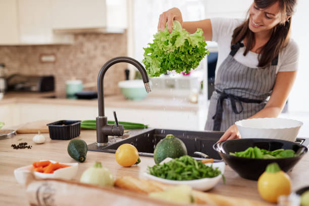 istock Woman washing salad in sink. 1162535606