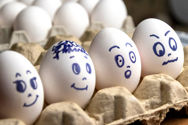 istock Lovely eggs in cardboard box. Eggs with emotions. White eggs in cardboard box with different faces painted on them. Boys and girl 1162535625