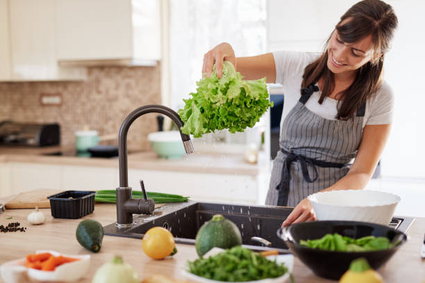 istock Woman washing salad in sink. 1162536855
