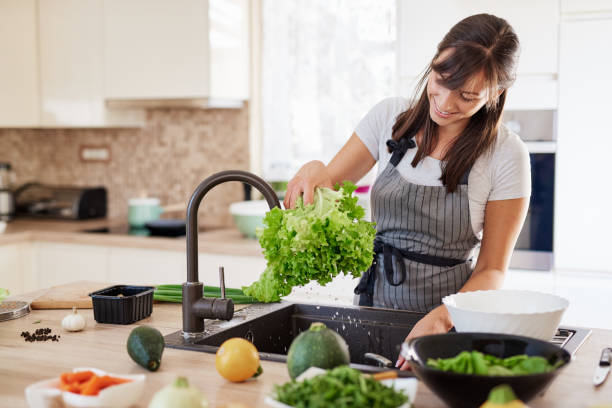 istock Woman washing salad in sink. 1162537038
