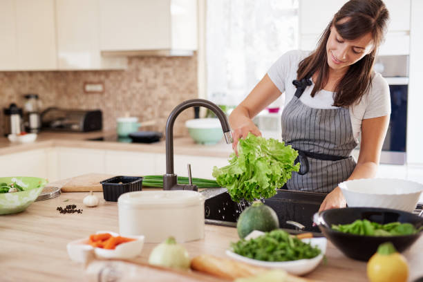 istock Woman washing salad in sink. 1162537071