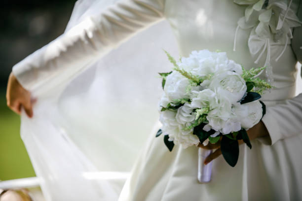 istock Bride in an white gown with bouquet in hands 1162539854