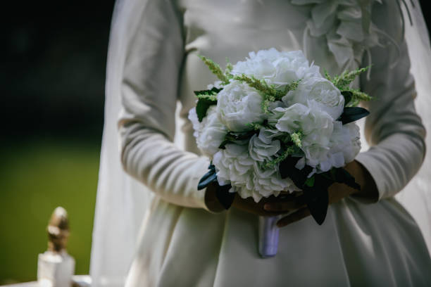 istock Bride in an white gown with bouquet in hands 1162539861