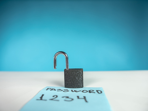 Unlocked padlock and note with weak password . The scene is situated in a studio environment in front of a colored background. The picture is taken with Panasonic GH5 camera
