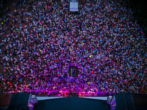 outdoor concert - colorful crowd of people in front of the stage, view from the drone