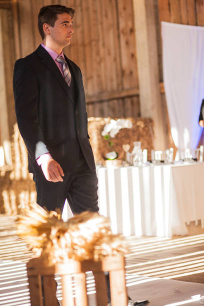 Young man in black suit talking on a wedding ceremony space.