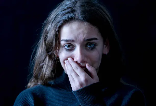 Dramatic closeup portrait of young scared, depressed girl crying alone, feeling hopeless suffering from harassment or domestic violence. Stop child abuse and neglect. Social campaign concept.