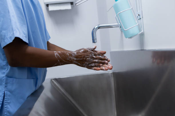 chirurgo maschio che si lava le mani nel lavandino in ospedale - lavarsi le mani foto e immagini stock