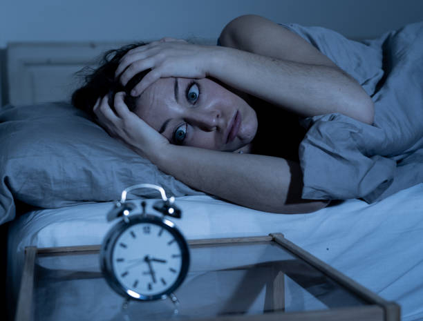 istock Sleepless and desperate beautiful caucasian woman awake at night not able to sleep, feeling frustrated and worried looking at clock suffering from insomnia in sleep disorder concept. 1162545708