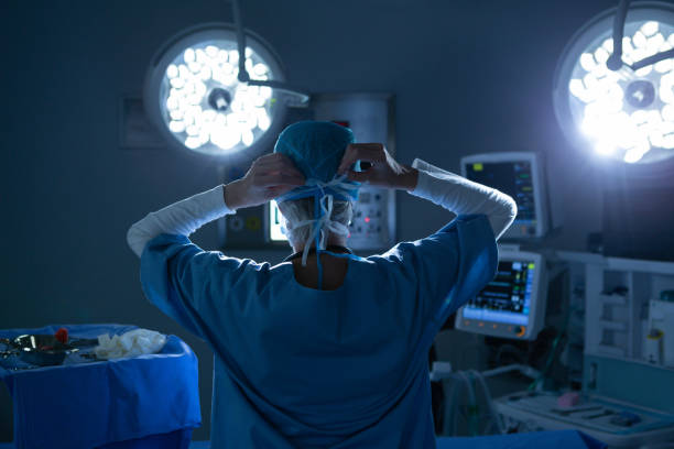 mujer cirujana usando mascarilla quirúrgica en el quirófano del hospital - cirujano fotografías e imágenes de stock