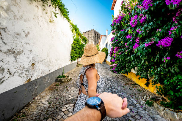 A walk in the streets of Obidos, Portugal A woman reaches back to her husband's hand and entices him to walk through the old town of Obidos discovering the narrow colorful streets and it's old structures. obidos photos stock pictures, royalty-free photos & images