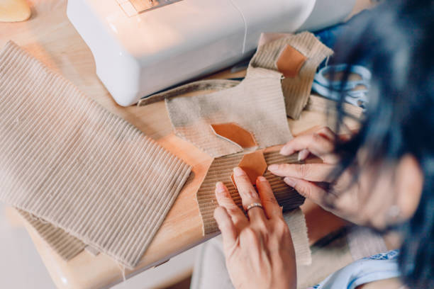 istock Female hands sewing fabric with needle at seamstress workplace of sewing process. hands stitching fabric on  machine hobby at home. blurred background. 1162554308
