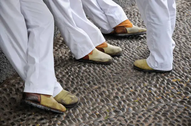 Photo of Carreiros waiting for costumers. Men dressed in white trousers with their typical shoes. Toboggan ride in Madeira