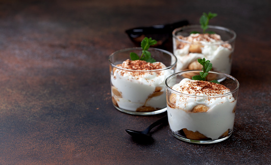 tiramisu in a glass with fresh mint on a brown background