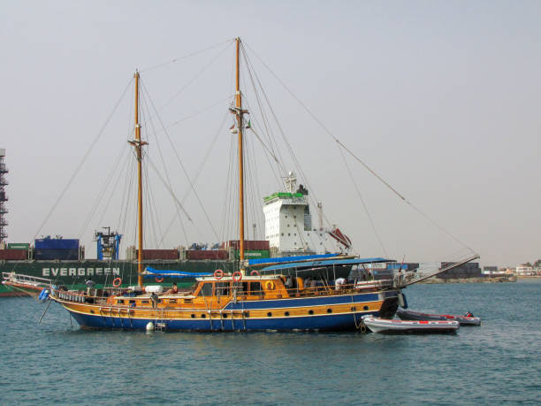Port Sudan, Sudan - May 2, 2010: Sailing boat and cargo ship in Port Sudan, northeastern Sudan. Port Sudan is the capital of the state of Red Sea the country's main port city. It was built in 1905 to replace the now ghost town of Suakin. The city has an oil refinery and handles the majority of the country's international trade, including the export of crude oil. Port Sudan is also a top destination for adventurous divers.