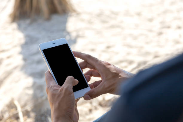 istock Close up hand man use mobile smart phone on the beach. Phone with black screen. With copy space for text or design 1162577613