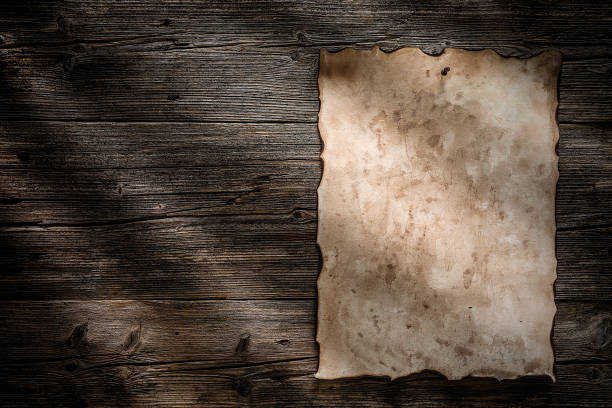 istock Old burnt parchment posted with pushpin to a wood background 1162582839