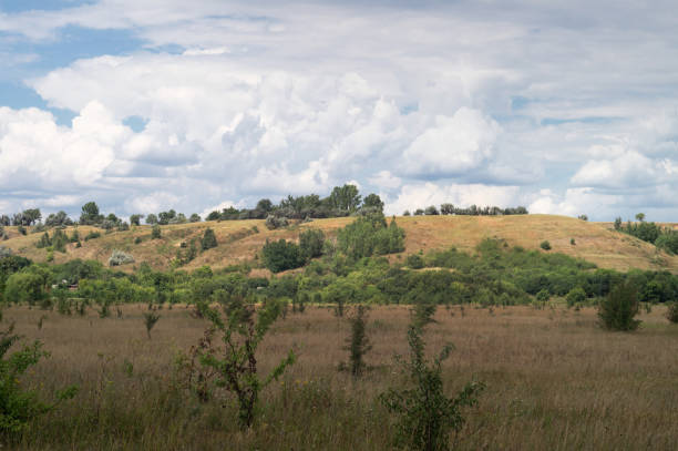 Clouds over scenic hills and meadows. Cloudy day in a picturesque summer valley.