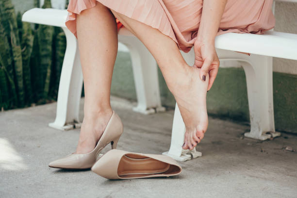 Woman suffering from leg pain outdoors because of uncomfortable shoes. Woman suffering from leg pain outdoors because of uncomfortable shoes. high heels stock pictures, royalty-free photos & images