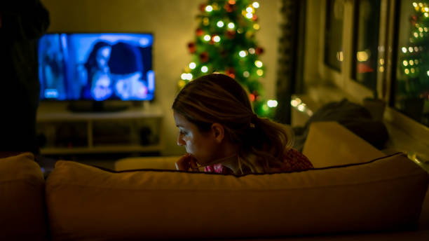 istock woman sitting on sofa in front of christmas tree 1162587634