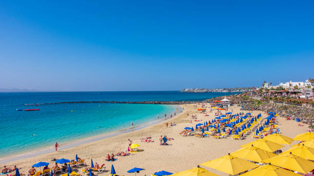 People enjoying a beautiful sunny day on the beach of Playa Blanca, a new and very popular tourist resort located in the south of Lanzarote.