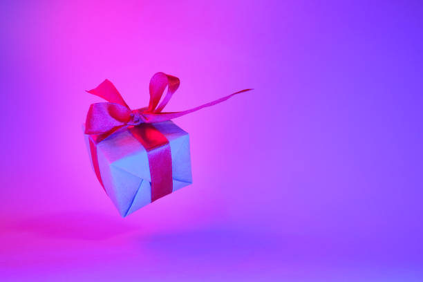 istock Gift box with red ribbon on trendy neon color background. zero gravity. levitation. copyspace. Concept sales, discount price, christmas presents and shopping 1162587789