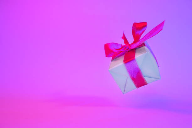 istock Gift box with red ribbon on trendy neon color background. zero gravity. levitation. copyspace. Concept sales, discount price, christmas presents and shopping 1162587893