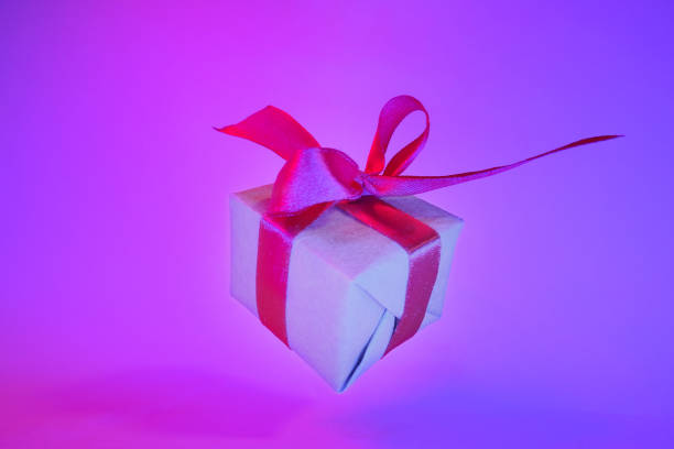 istock Gift box with red ribbon on trendy neon color background. zero gravity. levitation. copyspace. Concept sales, discount price, christmas presents and shopping 1162587894