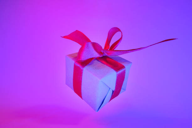 istock Gift box with red ribbon on trendy neon color background. zero gravity. levitation. copyspace. Concept sales, discount price, christmas presents and shopping 1162588519